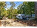 A white single story home with a covered porch, set back on a lot filled with mature trees at 1355 Woodland Sw Dr, Oxford, GA 30054