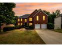 Stately two-story brick home with two-car garage, landscaped front yard, and warm interior lights at twilight at 1045 Paper Creek Dr, Lawrenceville, GA 30046