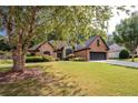 Brick and stone house with a large tree and landscaped yard at 305 Mogie Ln, Acworth, GA 30102