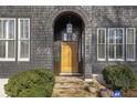 Close-up of front door featuring a lantern pendant, arched entryway, stone steps, and manicured landscaping at 5812 Long Park Rd, Cumming, GA 30040