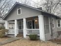 Charming home with a cozy front porch, classic columns, and neutral siding, nestled among mature trees at 1790 Spring Ave, East Point, GA 30344