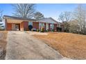 Ranch-style brick home with a long driveway, carport, and manicured bushes in the front yard at 6625 Imperial Dr, Morrow, GA 30260