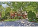 Stately brick home with lush landscaping, mature trees, and a long driveway at 959 Cedar Falls Sw Ct, Lilburn, GA 30047
