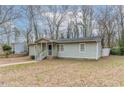 Single-story home with light green siding, a covered front porch with stairs, and a partially wooded front yard at 2366 Forrest Park Se Rd, Atlanta, GA 30315