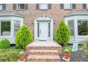 Charming brick entryway with a white front door, complemented by decorative plants and lush greenery at 830 Montego Sw Way, Lilburn, GA 30047