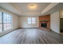 Bright living room featuring a brick fireplace, large windows, and elegant gray wood flooring at 1119 Summer Brook Rd, Atlanta, GA 30349