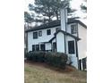 White two-story home with black trim and windows, nestled amongst trees at 911 David Dr, Lawrenceville, GA 30046