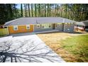Landscaped single-story home showcasing a large driveway, well-maintained lawn, and a mix of brown and gray exteriors at 681 Fielding Sw Ln, Atlanta, GA 30311