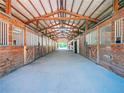 Interior of horse barn featuring a long corridor with stalls lining either side at 1820 Walker Sw Rd, Conyers, GA 30094