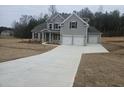 Charming two-story home featuring a three-car garage, gray siding, and a long, concrete driveway at 3292 Lions Ruby Ln, Atlanta, GA 30349