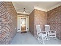 Inviting front porch featuring rocking chairs and brick flooring with wooden front door at 3377 Fielders Point, Dacula, GA 30019