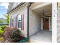 Brick front porch with a wooden door and purple shutters at 601 Cork St, Woodstock, GA 30188