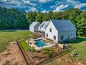Aerial view of a white farmhouse-style home with a pool, a detached garage, and a spacious lawn at 2731 Tribble Mill Rd, Lawrenceville, GA 30045