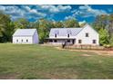 White farmhouse with metal roof, detached garage, and large backyard at 2731 Tribble Mill Rd, Lawrenceville, GA 30045