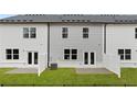 Backyard view of townhomes featuring a lawn, patios, and partial fencing for privacy at 353 Sound Cir, Stockbridge, GA 30281