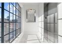 Bright hallway with elevator, large window and square mirror with gold trim above white wainscoting and marble floors at 234 Vickery Falls Dr, Roswell, GA 30075