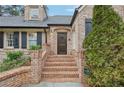Elegant brick entryway featuring a wooden front door and manicured landscaping at 3930 Peachtree Dunwoody Ne Rd, Atlanta, GA 30342