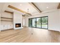Open living room with a fireplace, exposed wood beams, large sliding doors, and hardwood floors at 200 Heatherton Way, Milton, GA 30009