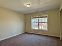 This bedroom has neutral walls and carpet with a window that offers natural light and a neighborhood view at 7972 Applemist Dr, Fairburn, GA 30213