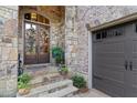 Elegant front door with glass panels, surrounded by stone and brick, adjacent to the garage at 4508 Oakside Pt, Marietta, GA 30067