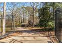 Gated driveway leads to a private home nestled among mature trees, offering seclusion and curb appeal at 3520 Still Rd, Cumming, GA 30041