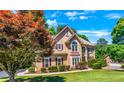 Two story house with tan siding, brown roof, and burgundy shutters at 234 Lake Ruby Dr, Suwanee, GA 30024