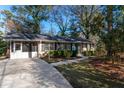 View of the home showcasing the driveway, a screened-in carport, and mature trees surrounding the property at 3448 Montreal Way, Tucker, GA 30084