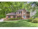 Charming brick two-story home boasts a well-manicured lawn, verdant landscaping, and a serene wooded backdrop at 4259 Arbor Club Dr, Marietta, GA 30066
