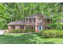 Charming brick two-story home features a manicured lawn, verdant landscaping, and a serene wooded backdrop at 4259 Arbor Club Dr, Marietta, GA 30066