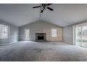 Spacious living room featuring a stone fireplace, ceiling fan, and bright windows at 180 Sears Cir, Covington, GA 30016