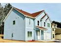 Side view of a two-story home with light blue siding, white trim, and a red roof, set on a grassy lot at 4405 Belcamp Rd, Fairburn, GA 30213