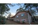 Side view of brick ranch house with pink shutters and mature trees at 5737 Lorraine Dr, Stone Mountain, GA 30087