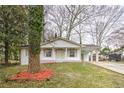 Quaint white brick home with neutral trim and a covered carport, set on a lot with mature trees at 6565 Bussell Way, Riverdale, GA 30274