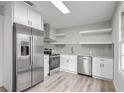 Modern kitchen with stainless steel appliances, white cabinets, gray subway tile backsplash, and floating shelves at 6565 Bussell Way, Riverdale, GA 30274