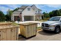 Two-story home with a three-car garage featuring light-colored brickwork with construction dumpsters in the front at 679 Crest Line Trl, Powder Springs, GA 30127
