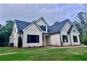 Low angle of the new construction home with traditional architecture, black shutters, neutral siding, and well-maintained lawn at 130 West Lake Blvd, Carrollton, GA 30116