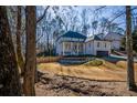 Two-story brick home with front porch and attached garage, nestled amongst mature trees at 1496 Sweet Bottom Sw Cir, Marietta, GA 30064