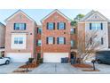 Charming brick townhome with a two-car garage and black shutters adding a touch of elegance to the facade at 1605 Signal Flag Way, Lawrenceville, GA 30043