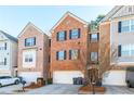 View of the brick townhome exterior with black shutters, a two car garage, landscaping, and a front door at 1605 Signal Flag Way, Lawrenceville, GA 30043