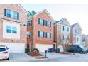 View of the brick townhome exterior with black shutters, a two car garage, landscaping, and a front door at 1605 Signal Flag Way, Lawrenceville, GA 30043