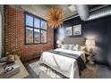 Cozy bedroom featuring exposed brick wall, large window, and stylish light fixture at 640 Glen Iris Ne Dr # 515, Atlanta, GA 30308