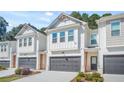 Two-story townhome with white siding, dark gray garage doors, and landscaping at 5536 Rockfern Dr, Lilburn, GA 30047