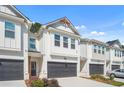 Two-story townhome with white siding, dark gray garage doors, and landscaping at 5536 Rockfern Dr, Lilburn, GA 30047