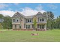 Two-story home with gray siding and brick accents, a front porch, and a grassy lawn at 26 Homesite Cooper E Cv, Fayetteville, GA 30214