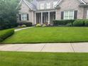 Well-manicured front lawn leading to a stately brick home with a covered entrance and mature landscaping at 6163 Talmadge Nw Run, Acworth, GA 30101