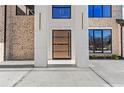 Close up of a modern front door with sleek design and glass panels, flanked by elegant light fixtures at 2753 Camp Branch Rd, Buford, GA 30519