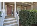 Inviting front porch with a red front door, white railings, stone accents, and neatly trimmed shrubs at 54 Etham Pl, Douglasville, GA 30134