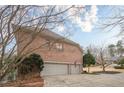 Three-car garage adjacent to the brick home featuring an expansive driveway, surrounded by mature landscaping at 5216 Old Mountain Ln, Powder Springs, GA 30127