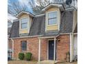 Charming brick townhome featuring a black front door, dormer windows, and mature landscaping at 8690 Ashley Way, Douglasville, GA 30134