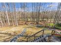 Secluded backyard with a stone path leading to a firepit and seating area near the edge of a wood-lined property at 775 River Cliff Ct, Suwanee, GA 30024